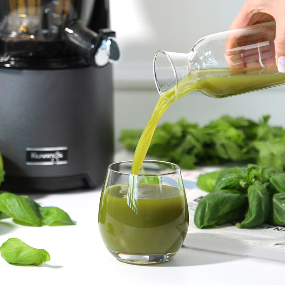 green juice from glass bottle is pouring in cup