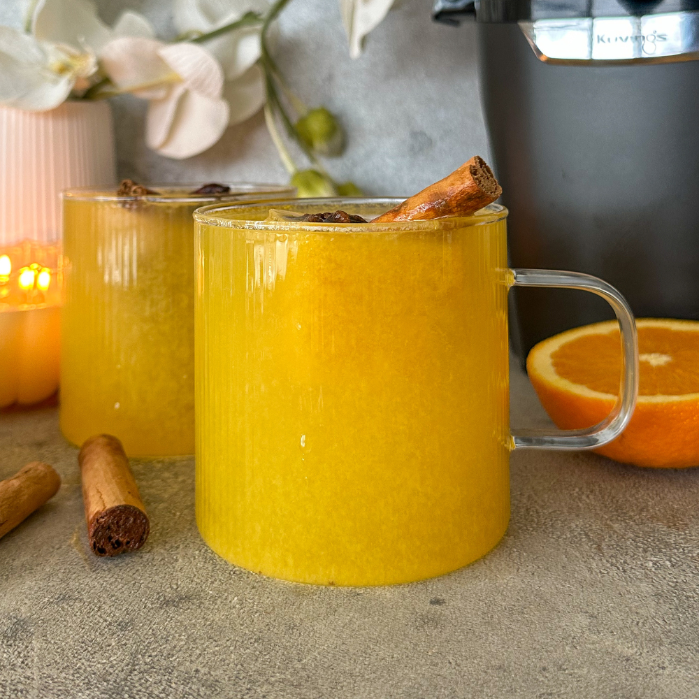 A glass of citrus tea with cinnamon sticks