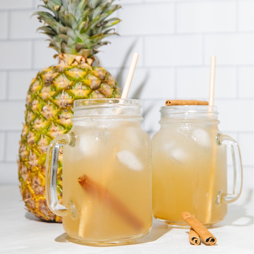 2 glasses of iced pineapple peel cinnamon tea in front of a pineapple