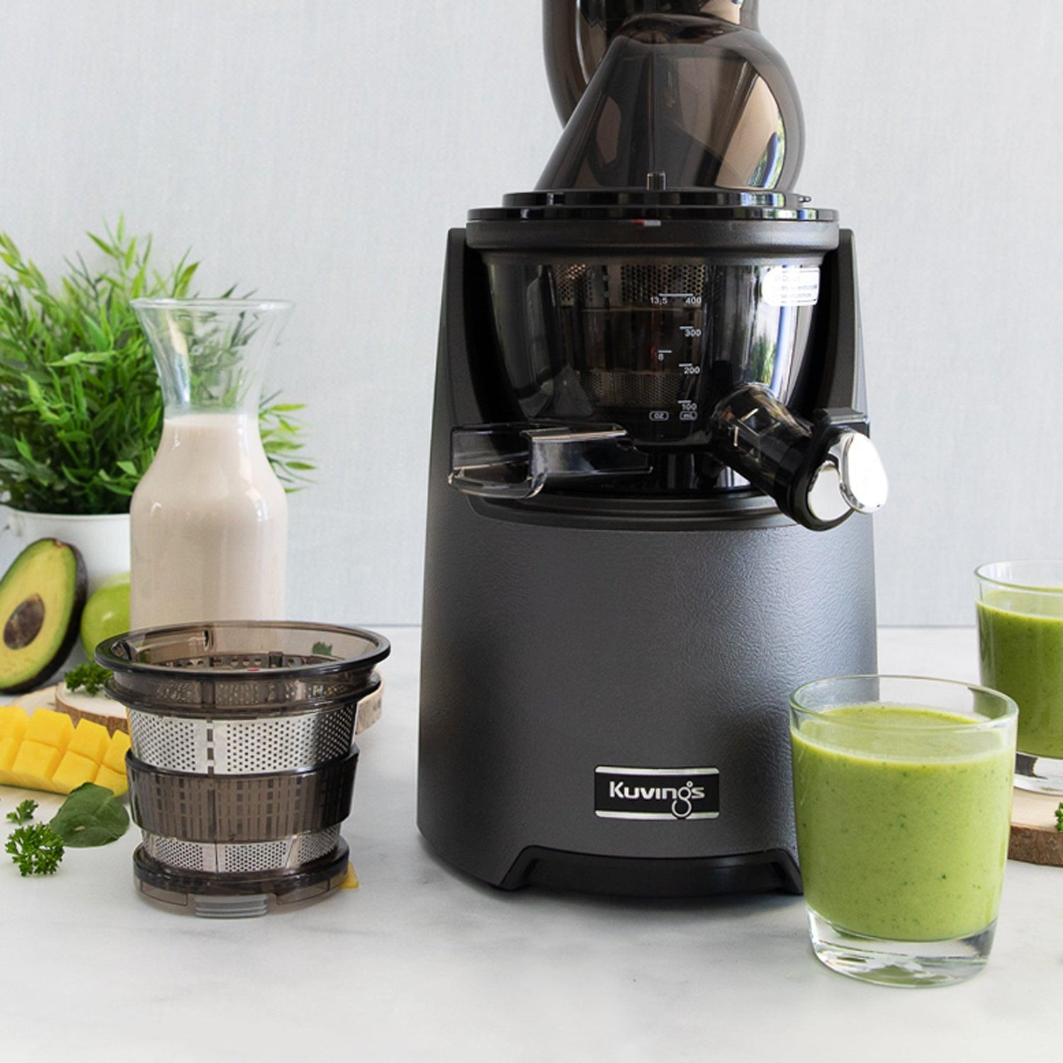 blueberry avocado smoothie next to juicer with avocado and blueberries surrounding