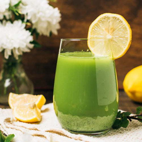 green juice with lemon slice and white flowers in background