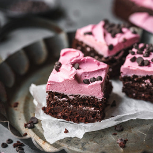 Brownie squares with pink frosting and chocolate chips as garnish.