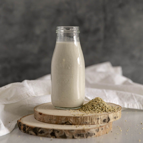 Bottle of hemp seed milk with scattered hemp seeds