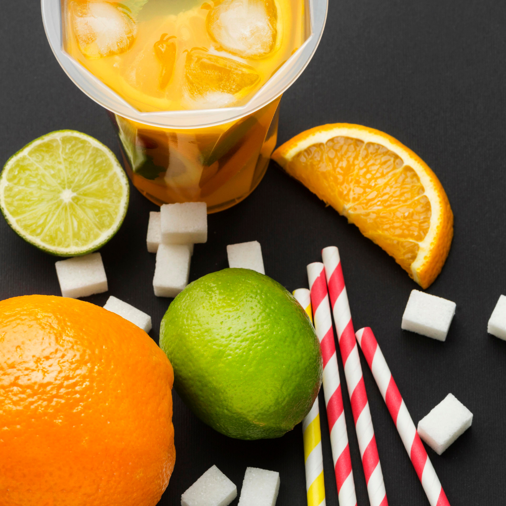 top view of a cup of juice, fruits, straws, and sugar squares