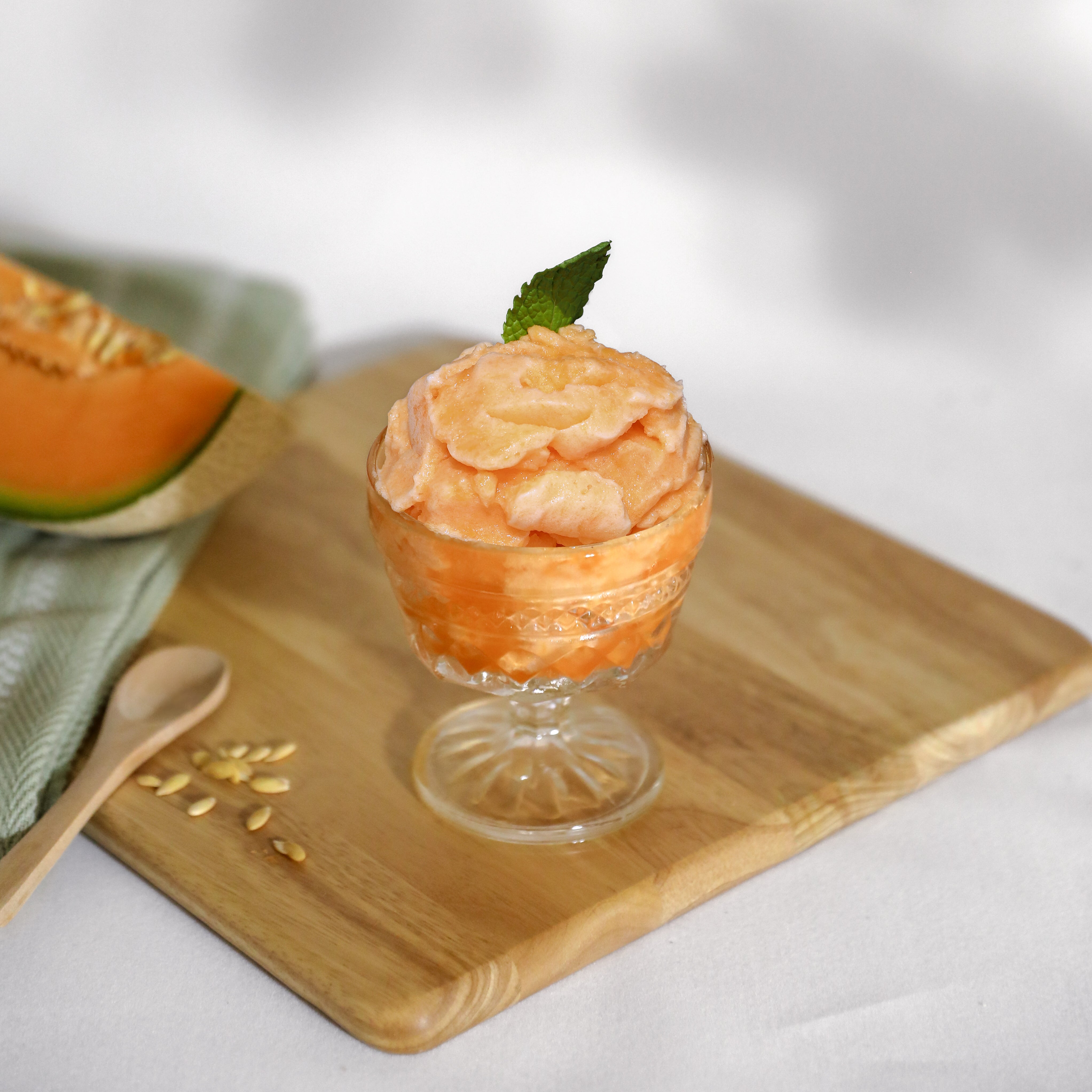 Cantaloupe sorbet in a glass cap on a cutting board