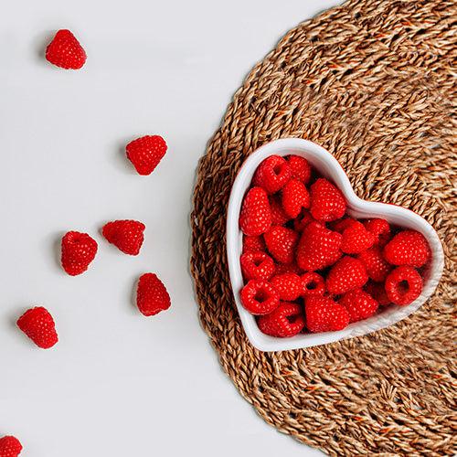 red raspberries in a heart-shaped bowl