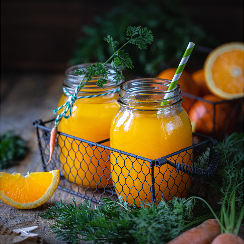 carrot juice with orange in a glass jar in a metal basket on a dark wooden background