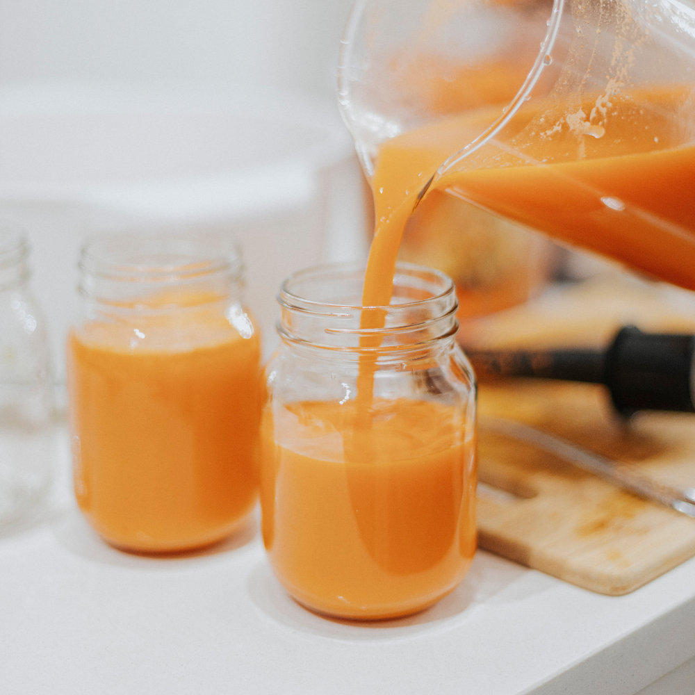 cold-pressed orange juice poured from a pitcher to a mason jar