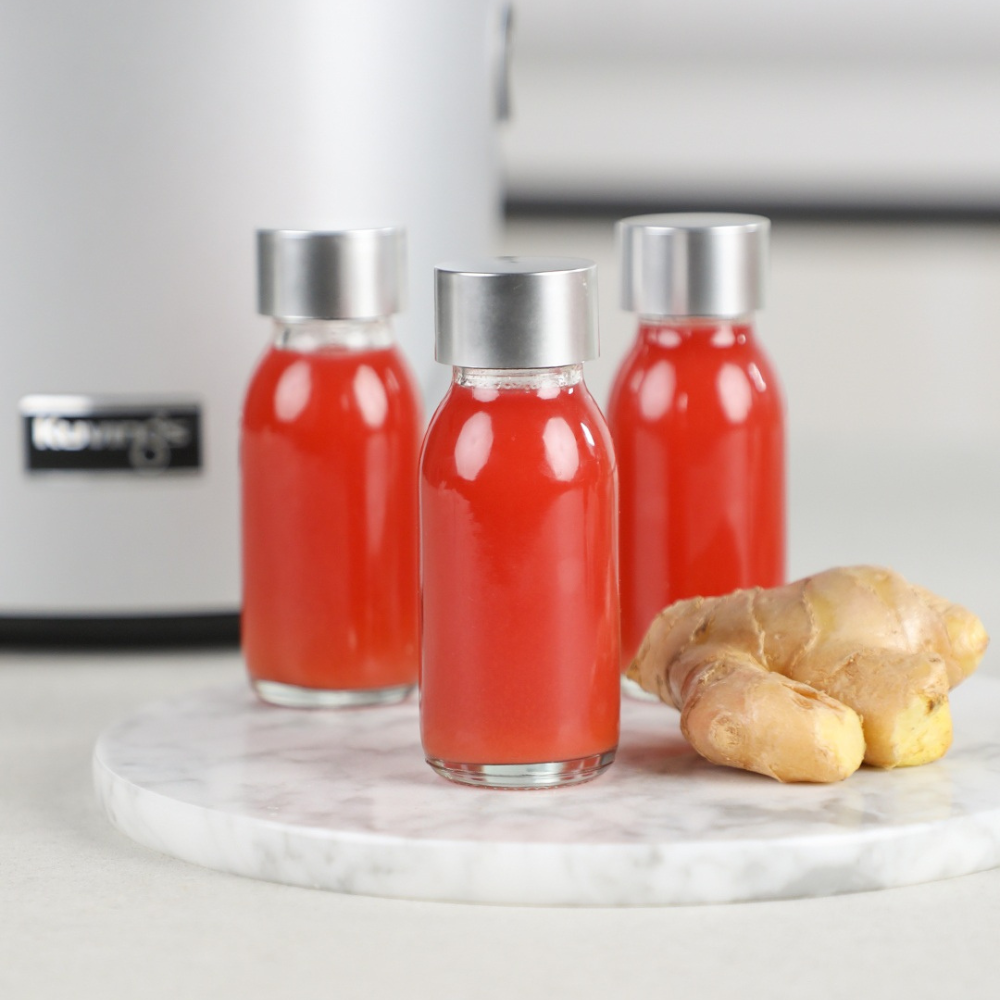 3 red juice shots and a piece of ginger