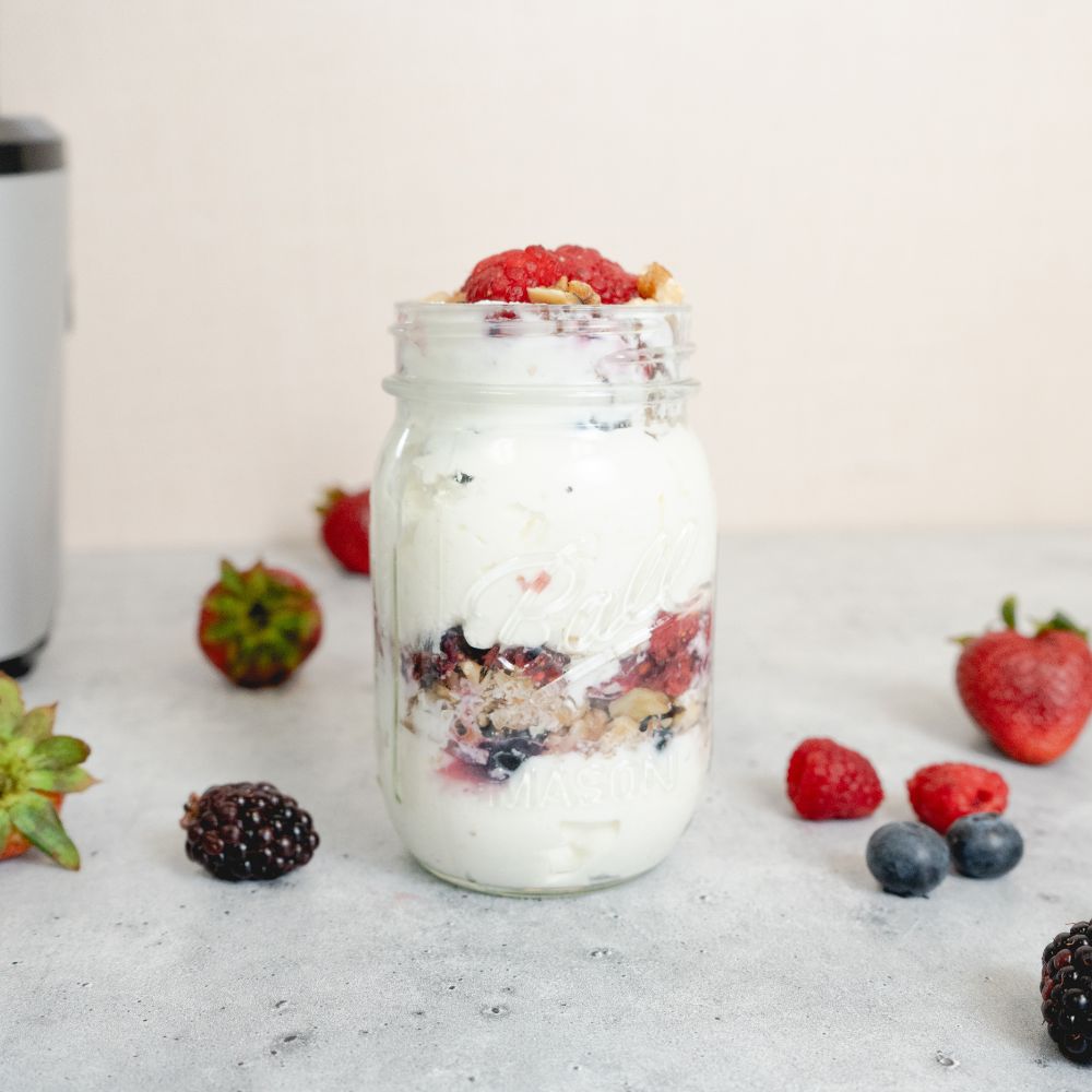 yogurt parfait in a mason jar with berries surrounding