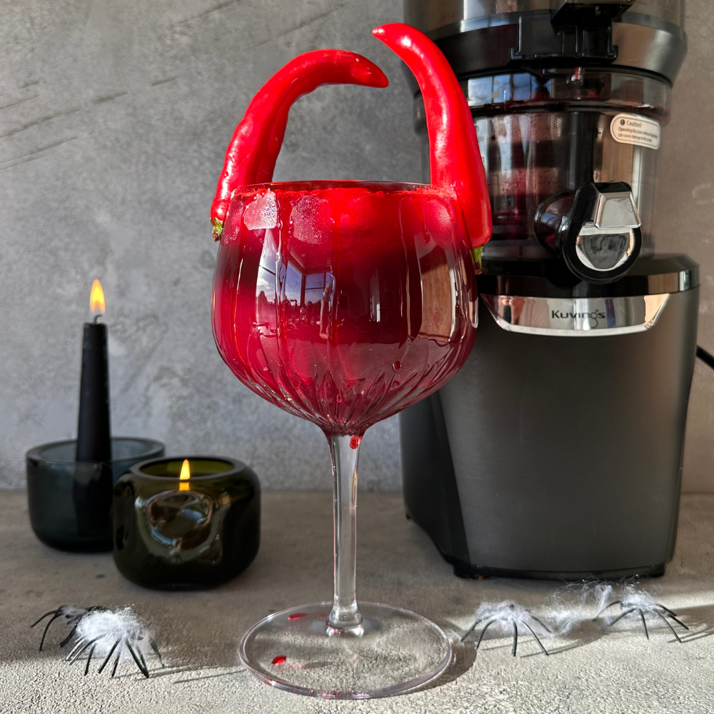 Red juice in a wine glass with red chili horns