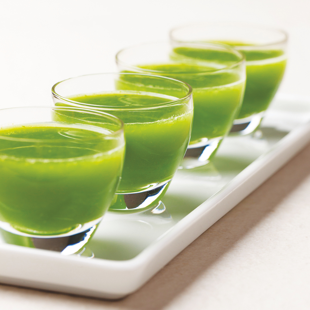 4 glasses of detox green juice on a white tray