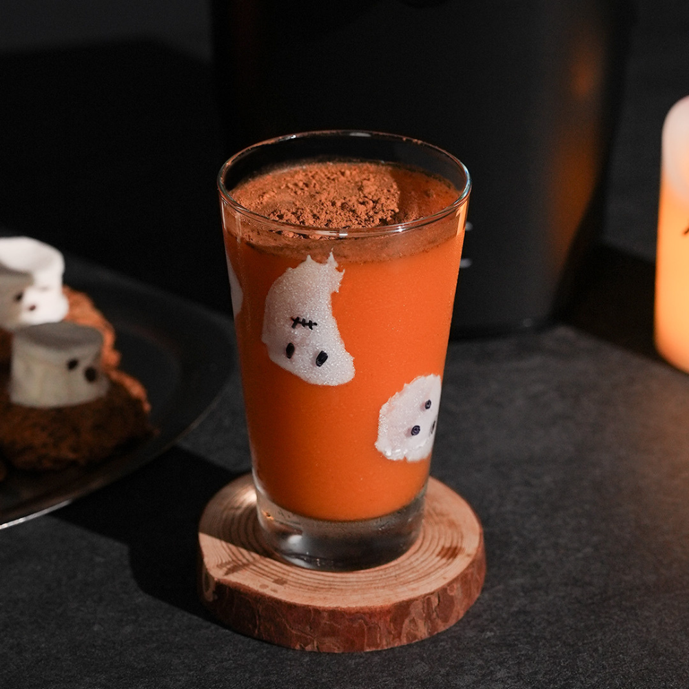 A glass of pumpkin juice in a ghost-decorated glass