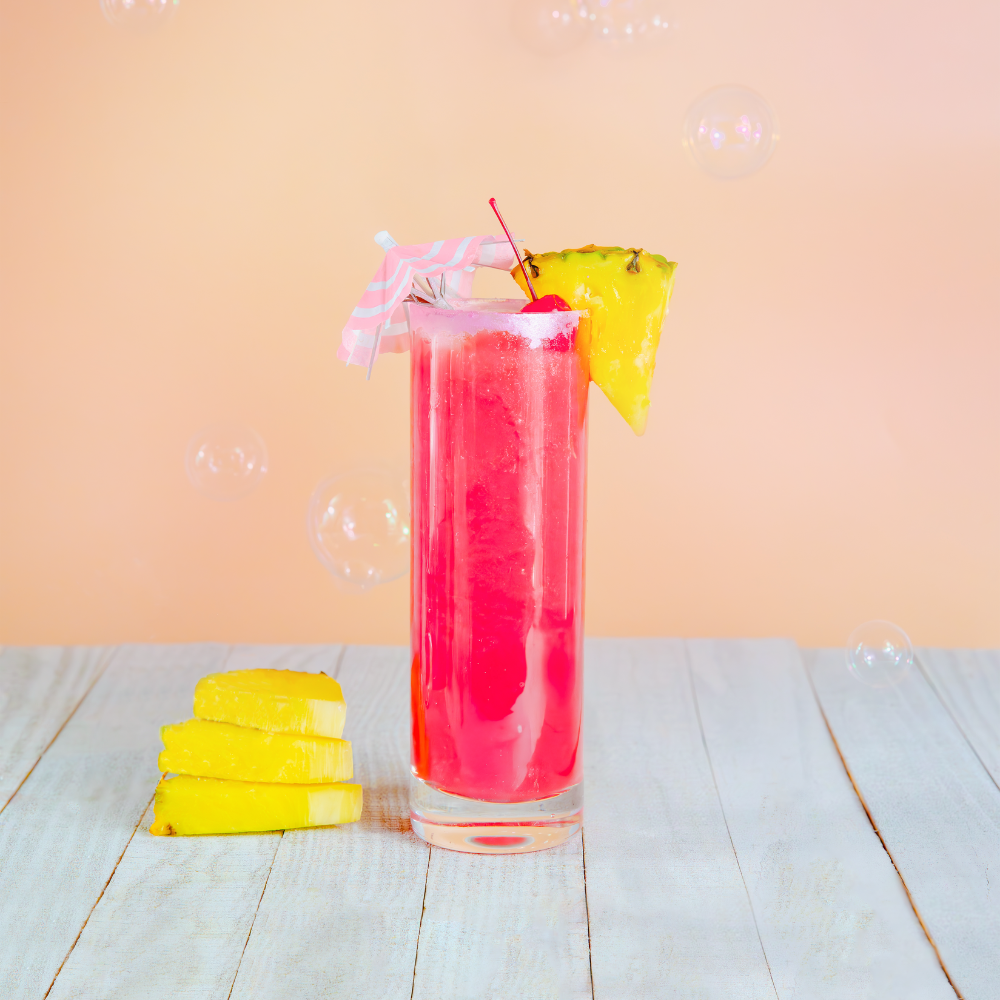 Red pink drink in a tall glass with pineapple slices and bubbles