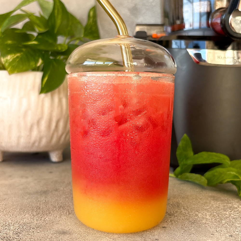 Red and yellow layered drink in a cold glass