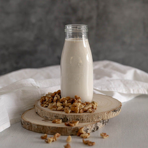 Bottle of walnut milk with scattered walnut pieces
